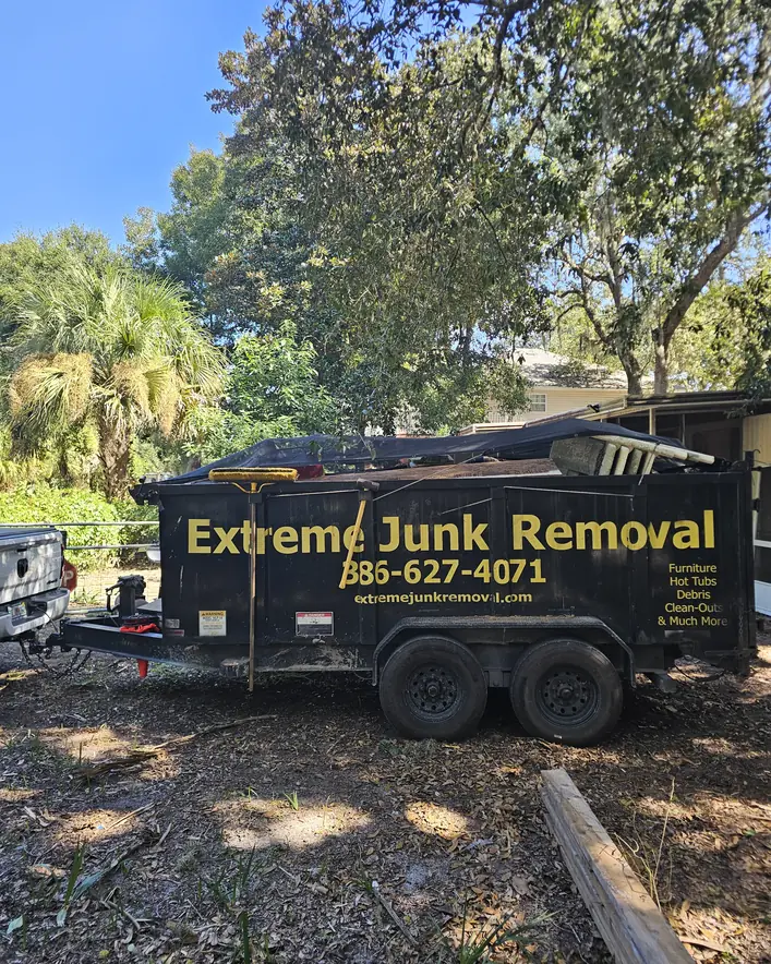 Extreme Junk Removal dump trailer loaded with yard debris in a backyard