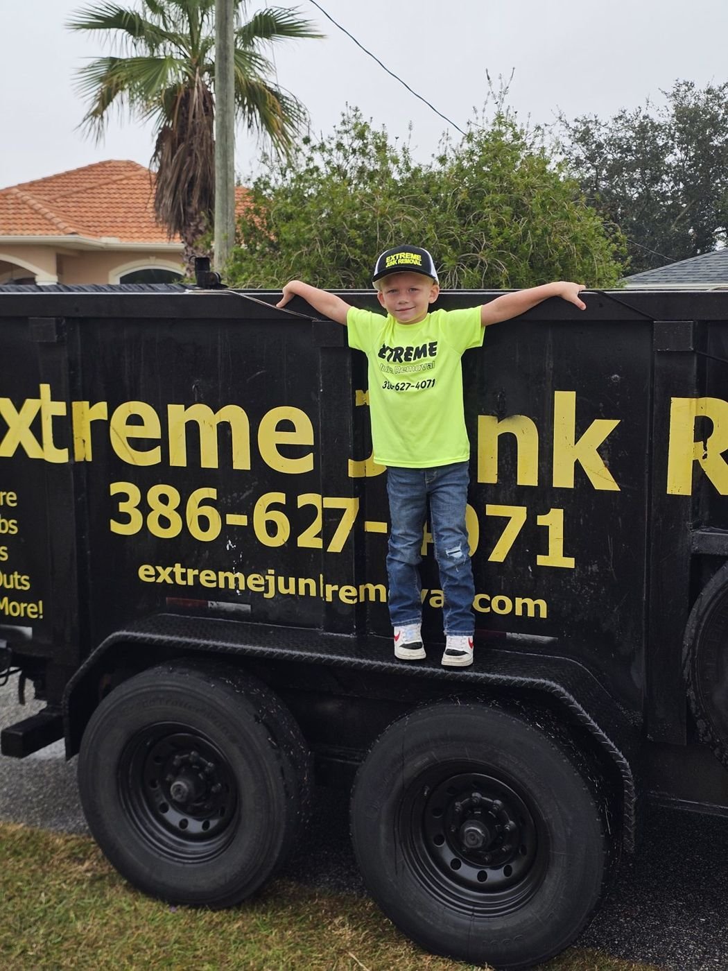 One of the kids from the Jeckovich family standing on the Extreme Junk Removal dump trailer in Palm Coast