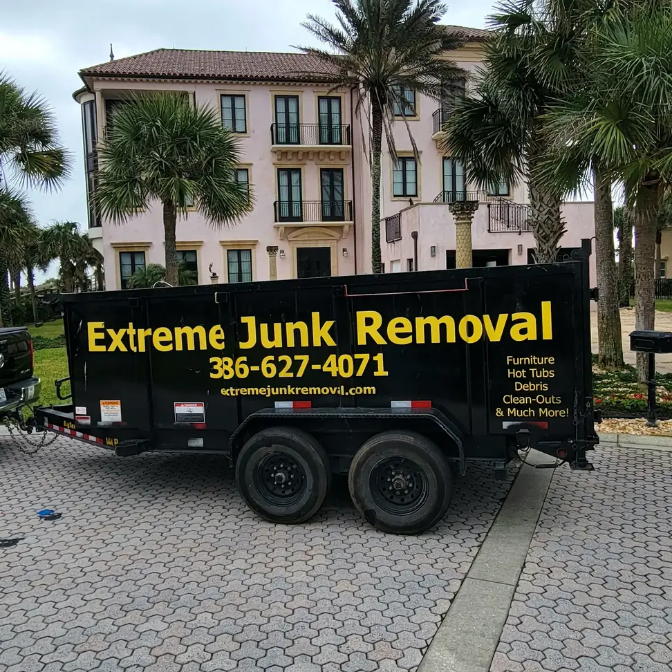 Extreme Junk Removal dump trailer with the phone number 386-627-4071 on the side, serving Palm Coast to New Smyrna Beach