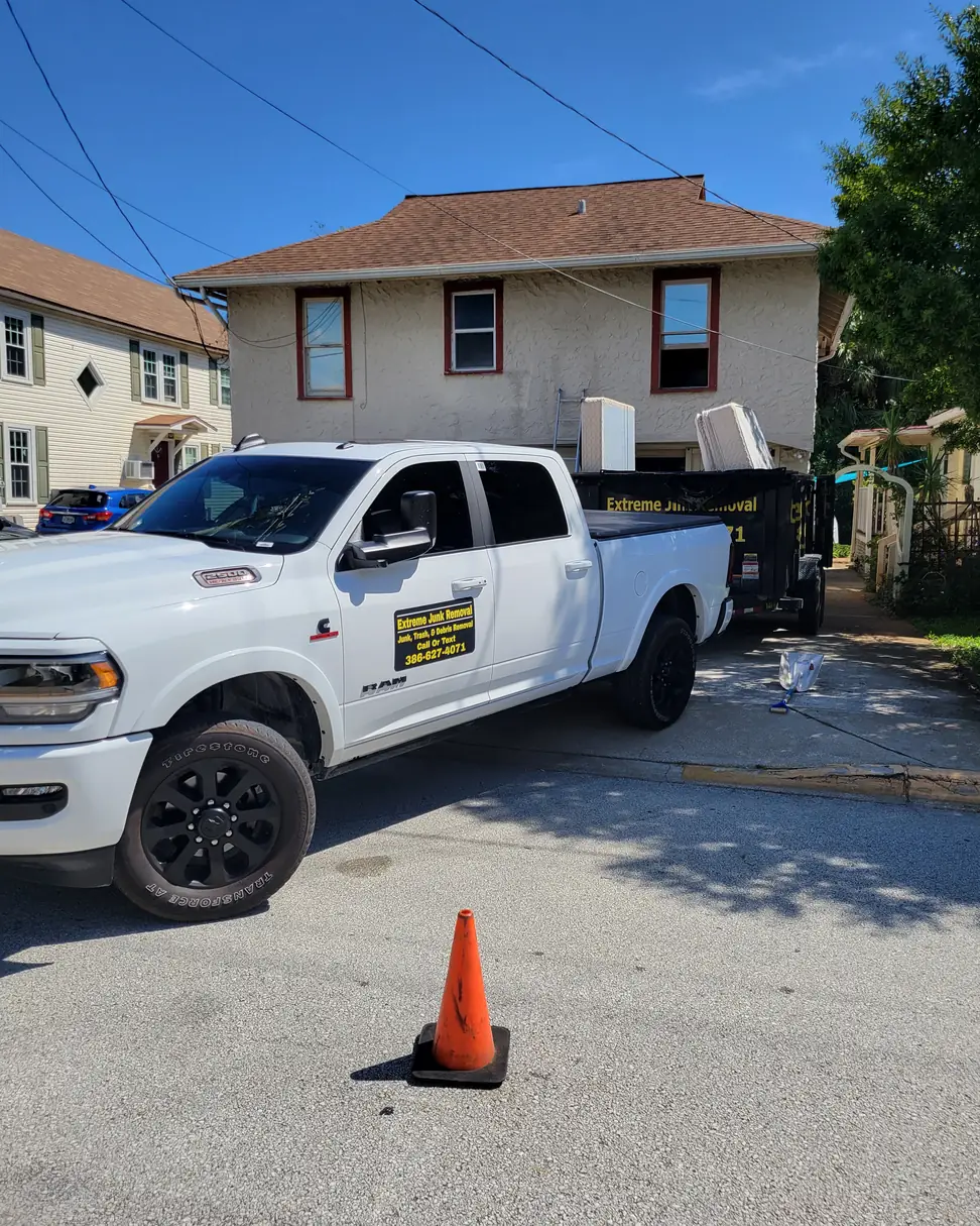 Extreme Junk Removal truck and loaded dump trailer on a residential street, serving Palm Coast to New Smyrna Beach