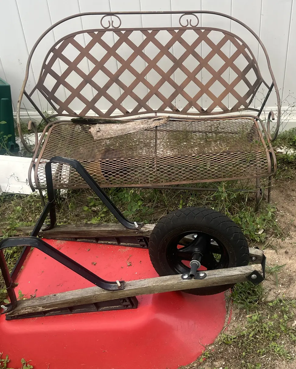 Old metal garden bench and a rusted wheelbarrow ready for haul away